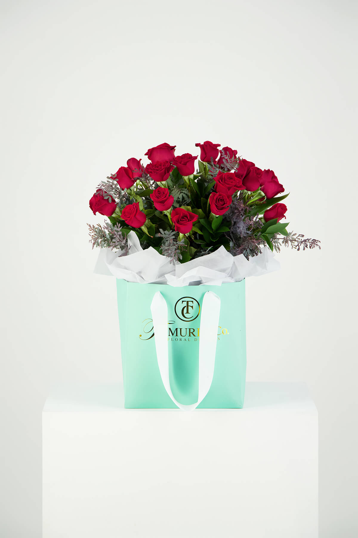 Red roses photographed in blue box packaging with gold foiling