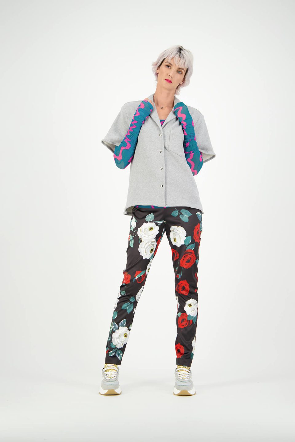 Women's fashion model studio photoshoot wearing floral pants and grey button up tee-shirt